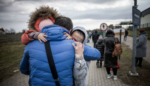 A man hugs his daughter and grandaughter after they crossed the border from Shehyni in Ukraine to Medyka in Poland.