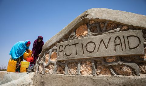 Amina (left) fills up her jerry cans with some water provided by ActionAid, after severe drought killed off her livestock and crops in Somaliland in 2022.