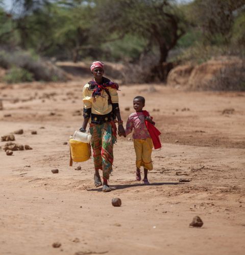 Consolata, with her daughter Elizabeth, 7, carrying jerry cans from the watering hole back to their home in Kenya.